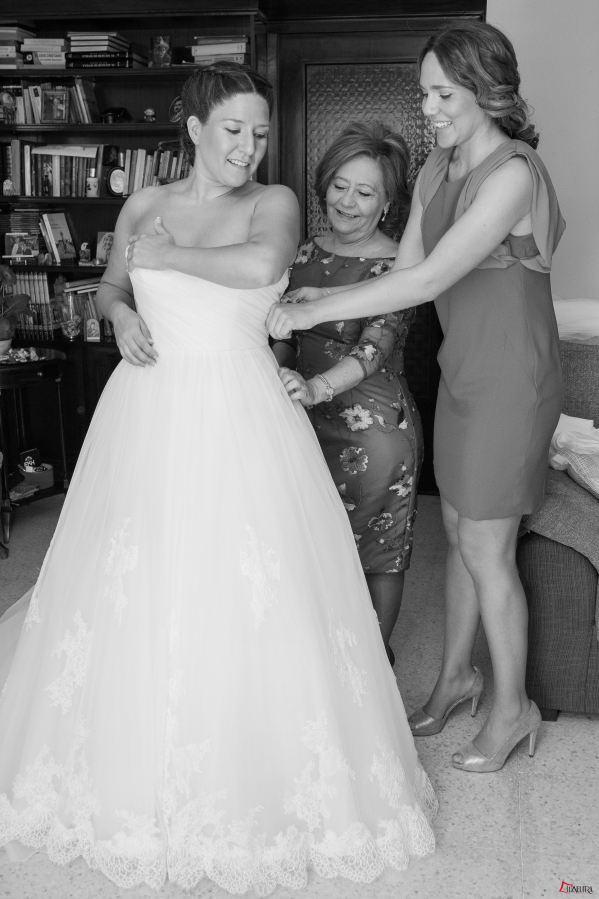 La madre y la hermana de la novia la ayudan a vestirse